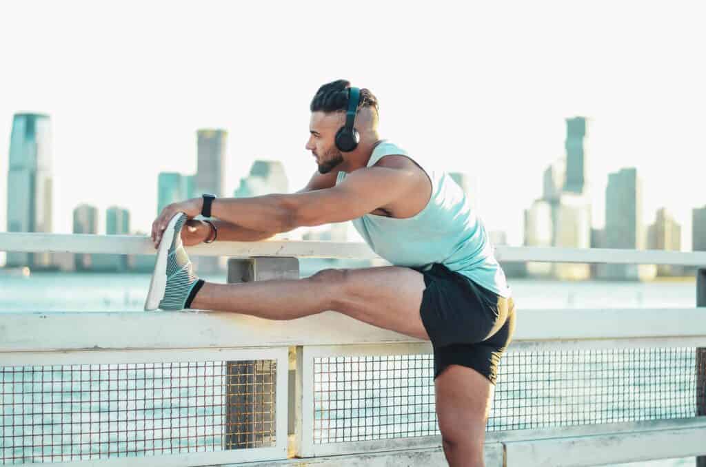 man stretching his hamstring on a fence